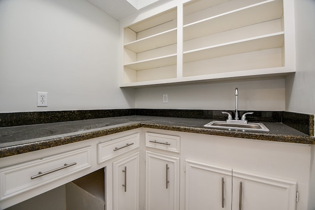 kitchen with white cabinetry, sink, and dark stone counters