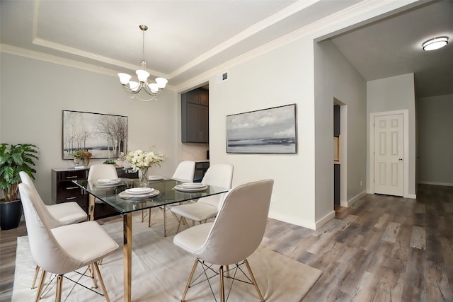 dining room featuring a raised ceiling, crown molding, an inviting chandelier, and hardwood / wood-style flooring