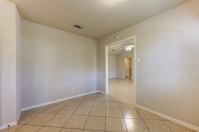 spare room featuring ceiling fan, light tile patterned floors, and a textured ceiling