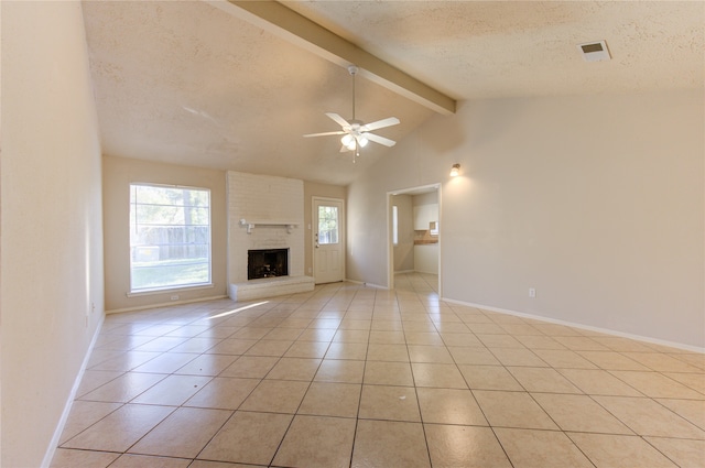 unfurnished living room with a brick fireplace, a textured ceiling, ceiling fan, vaulted ceiling with beams, and light tile patterned flooring