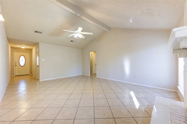 tiled empty room with a fireplace, lofted ceiling with beams, ceiling fan, and a healthy amount of sunlight