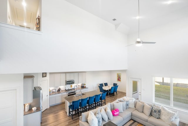 living room with ceiling fan, sink, dark hardwood / wood-style floors, and a high ceiling