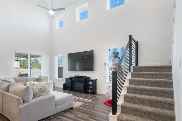 living room featuring ceiling fan, a towering ceiling, and hardwood / wood-style flooring