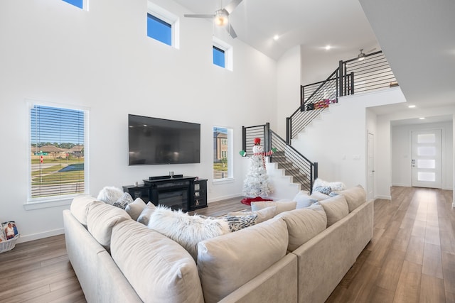 living room with ceiling fan, a high ceiling, and hardwood / wood-style flooring