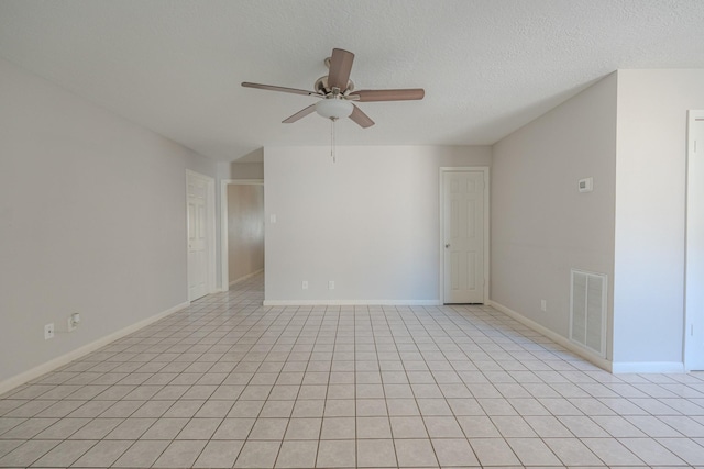 empty room with ceiling fan, light tile patterned flooring, and a textured ceiling