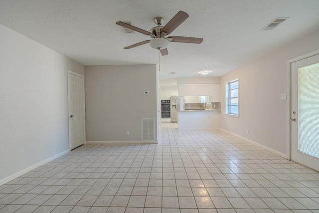 unfurnished living room with ceiling fan, light tile patterned floors, and a textured ceiling