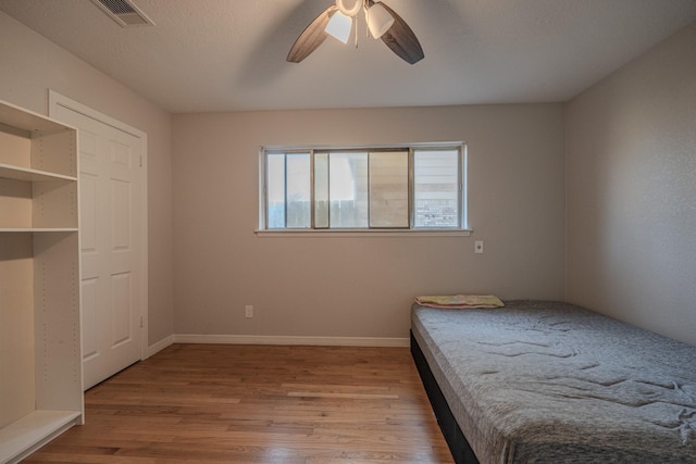 unfurnished bedroom featuring a textured ceiling, light wood-type flooring, and ceiling fan