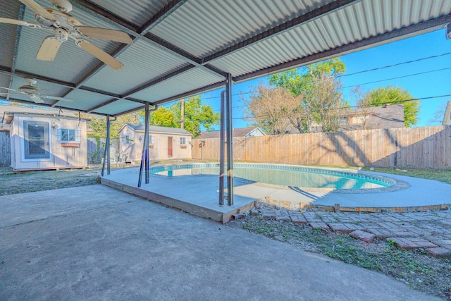 view of patio / terrace with a fenced in pool, ceiling fan, and a shed