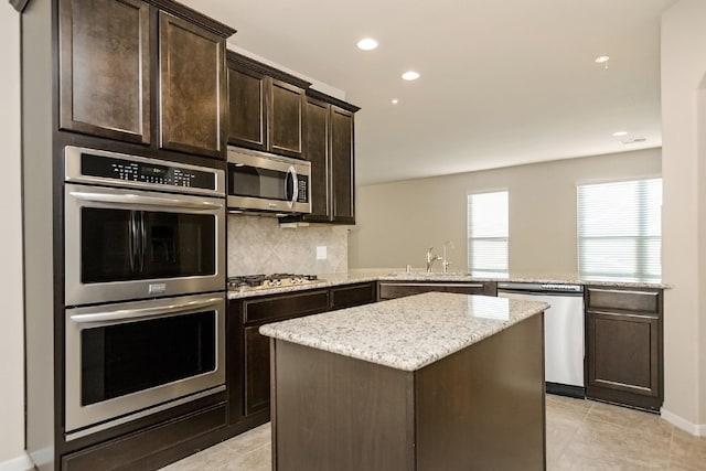 kitchen featuring dark brown cabinetry, sink, stainless steel appliances, tasteful backsplash, and a kitchen island