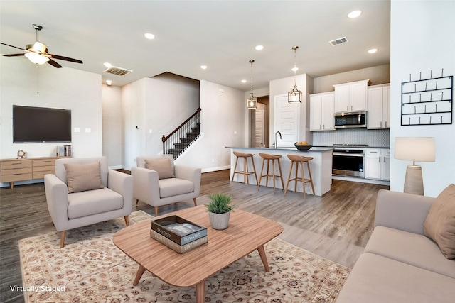 living room featuring sink, light hardwood / wood-style flooring, and ceiling fan