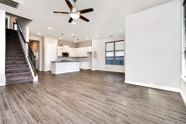 unfurnished living room featuring sink, dark hardwood / wood-style floors, and ceiling fan