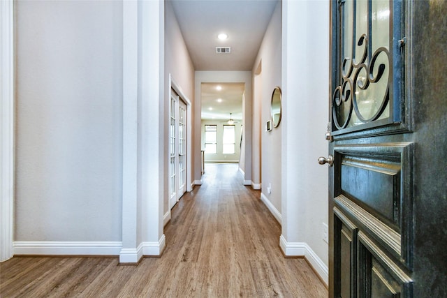 hall with french doors and light hardwood / wood-style floors