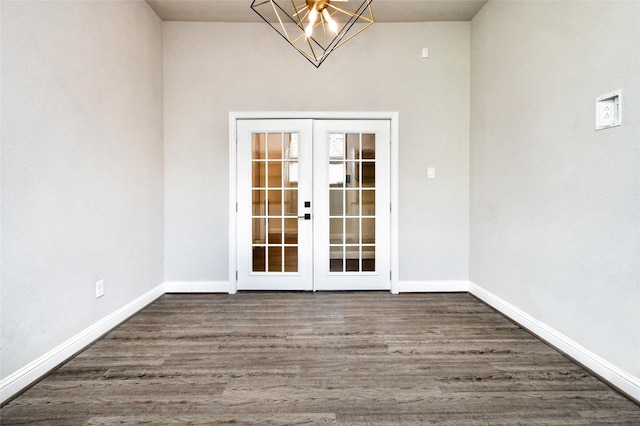 spare room featuring french doors, dark hardwood / wood-style flooring, and a chandelier