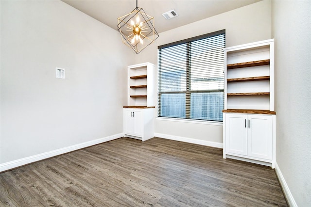 unfurnished dining area with an inviting chandelier and dark hardwood / wood-style flooring