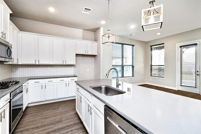 kitchen featuring stainless steel appliances, white cabinetry, sink, and decorative light fixtures