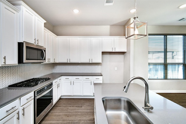 kitchen featuring sink, stainless steel appliances, dark hardwood / wood-style floors, white cabinets, and decorative light fixtures