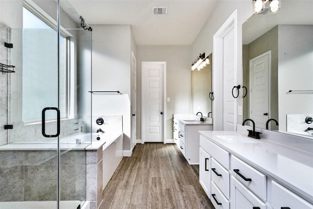 bathroom with wood-type flooring, separate shower and tub, and vanity