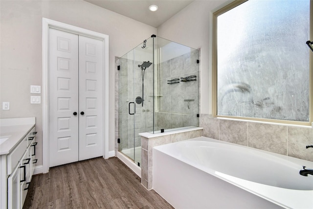 bathroom with plus walk in shower, hardwood / wood-style floors, and vanity