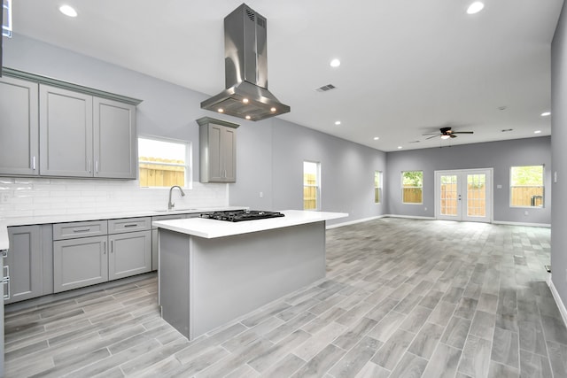 kitchen with island range hood, gray cabinets, a wealth of natural light, and light hardwood / wood-style floors