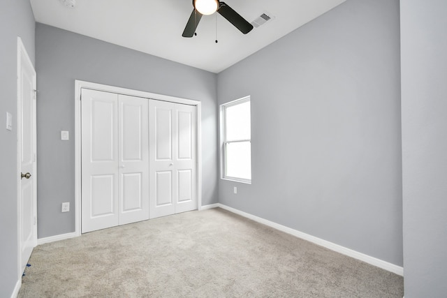 unfurnished bedroom featuring ceiling fan, a closet, and light carpet