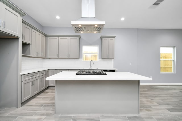 kitchen with gray cabinetry, backsplash, a kitchen island, and island exhaust hood