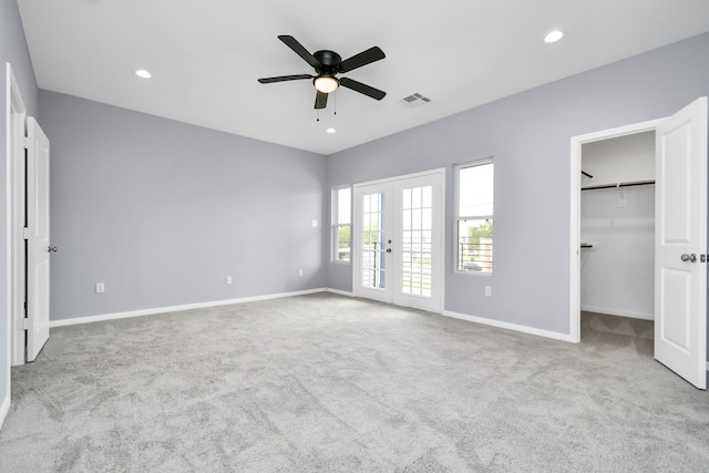 unfurnished bedroom featuring a spacious closet, french doors, ceiling fan, light colored carpet, and a closet