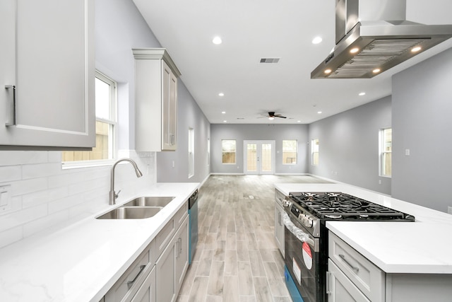 kitchen with ceiling fan, sink, light hardwood / wood-style flooring, island range hood, and appliances with stainless steel finishes