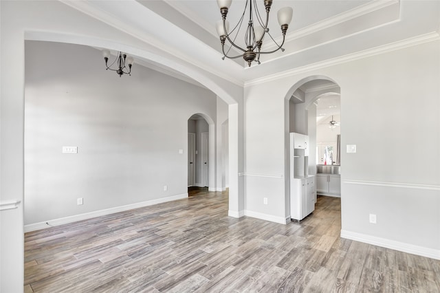 spare room featuring ceiling fan with notable chandelier, light wood-type flooring, and ornamental molding