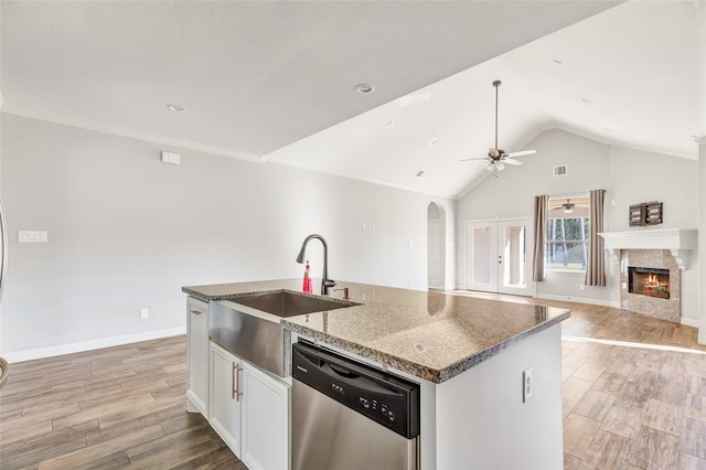 kitchen with dishwasher, light hardwood / wood-style flooring, lofted ceiling, a center island with sink, and white cabinets