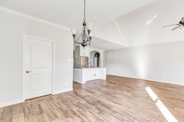 unfurnished dining area with ceiling fan with notable chandelier, light wood-type flooring, crown molding, and vaulted ceiling