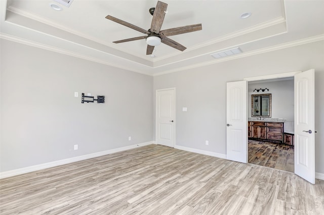 unfurnished room with ceiling fan, a raised ceiling, light wood-type flooring, and crown molding