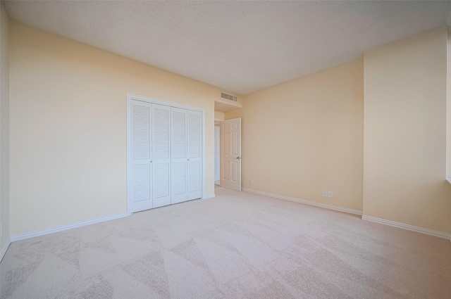 unfurnished bedroom with a closet and light colored carpet