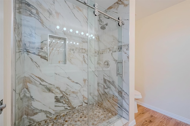 bathroom with an enclosed shower, toilet, and wood-type flooring