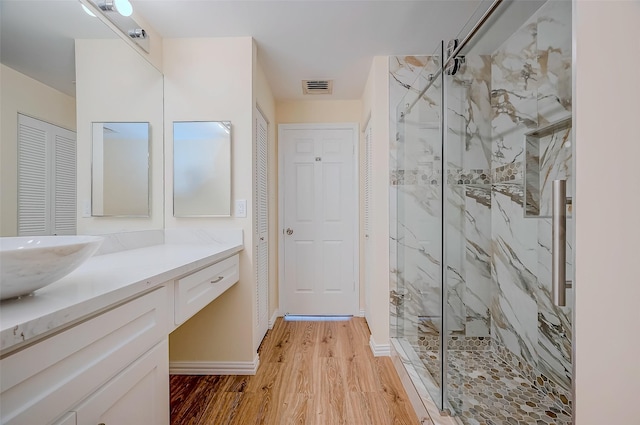 bathroom featuring vanity, a tile shower, and wood-type flooring