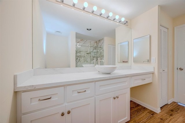 bathroom featuring hardwood / wood-style flooring, vanity, and tiled shower