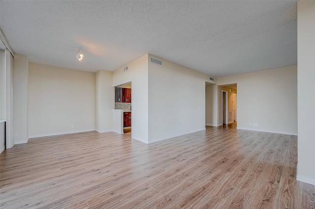 spare room with a textured ceiling and light hardwood / wood-style flooring