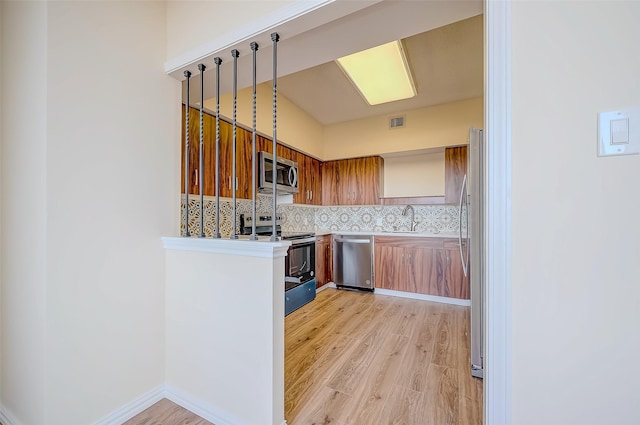 kitchen featuring decorative backsplash, sink, stainless steel appliances, and light hardwood / wood-style flooring