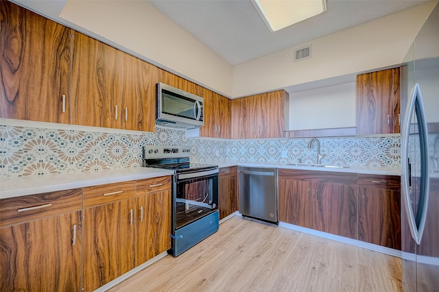 kitchen featuring backsplash, light hardwood / wood-style flooring, stainless steel appliances, and sink