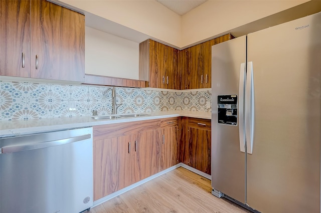 kitchen with backsplash, sink, appliances with stainless steel finishes, and light hardwood / wood-style flooring