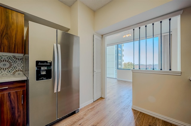 kitchen with backsplash, light hardwood / wood-style flooring, and stainless steel refrigerator with ice dispenser