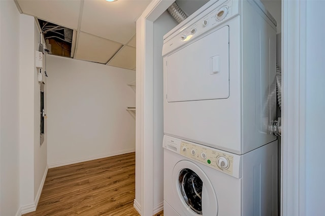 laundry area with stacked washer and dryer and light hardwood / wood-style flooring