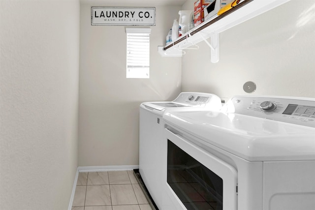 laundry area with washer and dryer and light tile patterned floors