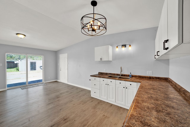 kitchen featuring vaulted ceiling, an inviting chandelier, white cabinetry, and sink