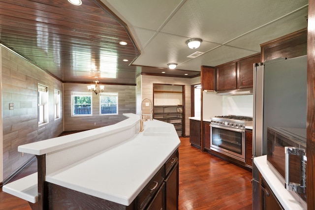 kitchen featuring sink, appliances with stainless steel finishes, a notable chandelier, a kitchen island, and dark hardwood / wood-style flooring