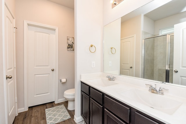 bathroom with hardwood / wood-style floors, vanity, toilet, and a shower with shower door