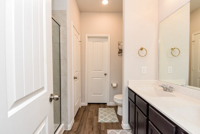 bathroom featuring wood-type flooring, vanity, toilet, and an enclosed shower