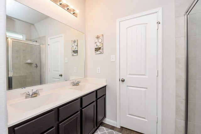 bathroom with hardwood / wood-style floors, vanity, and a shower with door