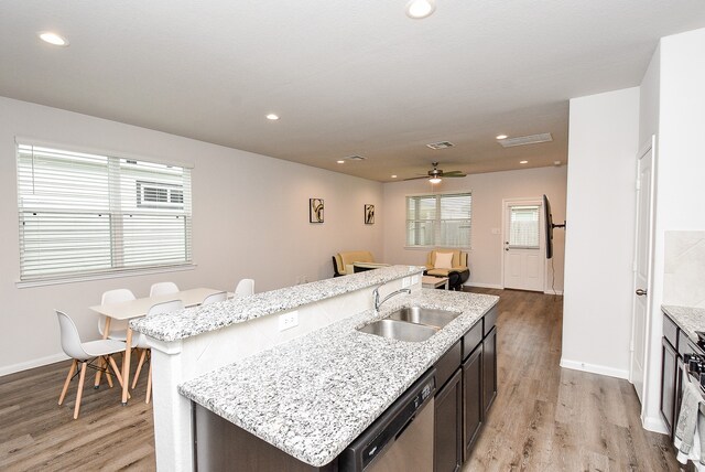 kitchen with a wealth of natural light, a kitchen island with sink, stainless steel dishwasher, and light wood-type flooring