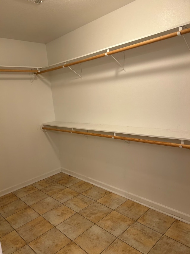 walk in closet with light tile patterned floors