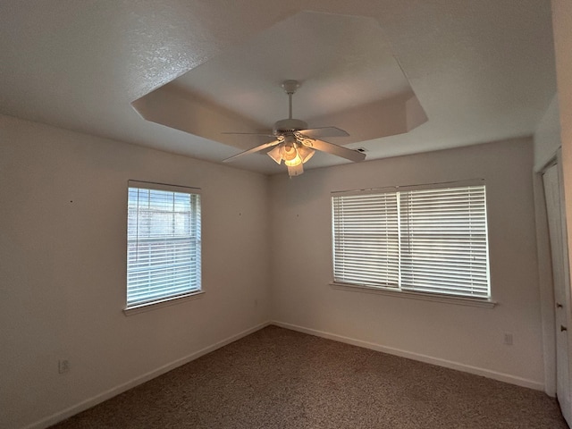 carpeted spare room featuring a textured ceiling, a raised ceiling, and ceiling fan